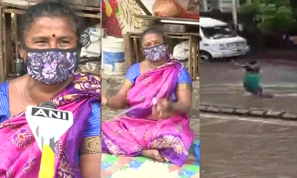 50 year old women stand in front of manhole hours among heavy rain and water logs ;  warning save lives of many ; country salute flower seller