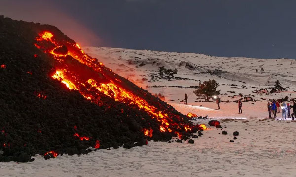 crowd of tourists gather to witness a lava flow